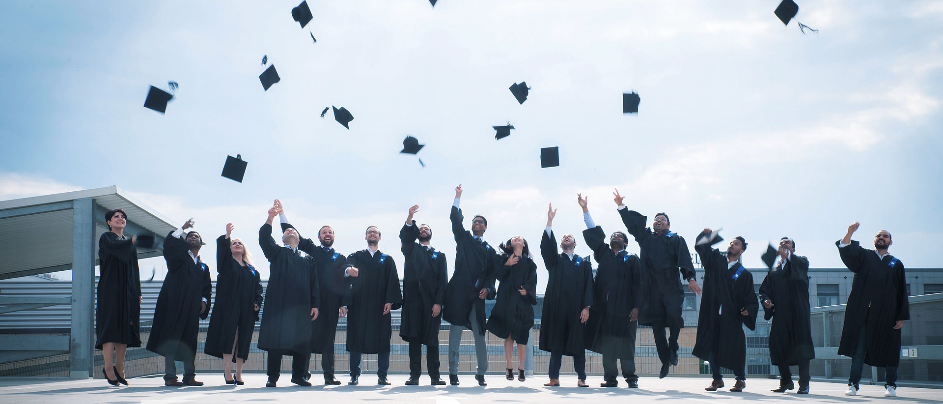 Das Bild zeigt MBA Studierende der OPS, welche ihre Abschlusshüte in die Luft werfen. 